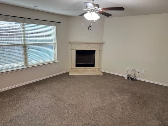 unfurnished living room with a fireplace with raised hearth, carpet flooring, a ceiling fan, and baseboards