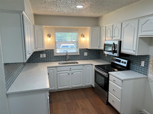 kitchen with stainless steel appliances, dark wood-style flooring, a sink, white cabinets, and light countertops