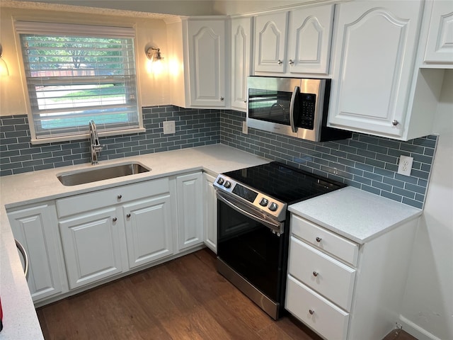 kitchen featuring stainless steel appliances, a sink, white cabinetry, light countertops, and dark wood-style floors