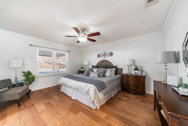 bedroom with light wood finished floors, visible vents, and crown molding