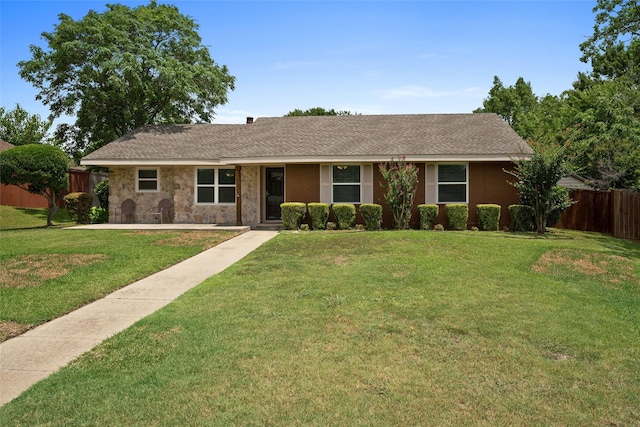 ranch-style house featuring stone siding, fence, a front lawn, and roof with shingles