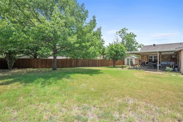 view of yard with an outbuilding, a patio area, a fenced backyard, and a storage shed