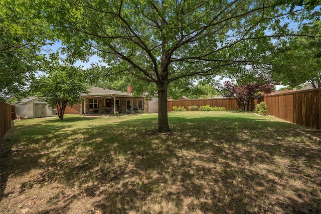 view of yard featuring a fenced backyard, an outdoor structure, and a shed