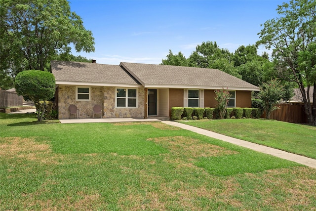 ranch-style home featuring a front yard, stone siding, roof with shingles, and fence