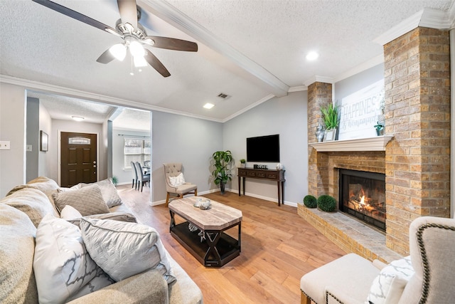 living room with vaulted ceiling with beams, ornamental molding, a textured ceiling, and light wood-style floors