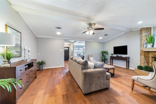 living area with lofted ceiling with beams, light wood-style floors, visible vents, and a textured ceiling