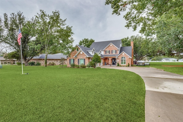 view of front of house featuring concrete driveway, brick siding, and a front lawn