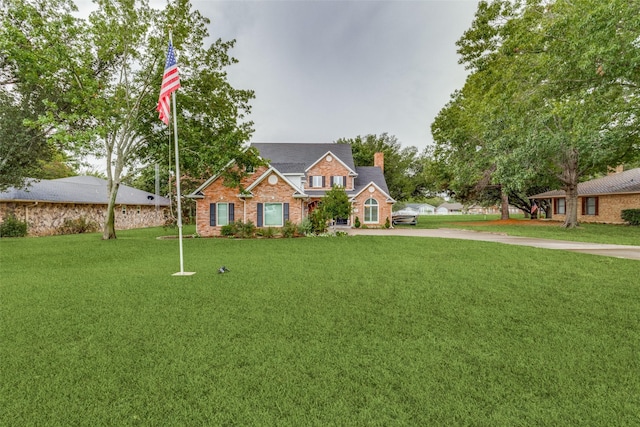 view of front of home with brick siding, a chimney, and a front yard