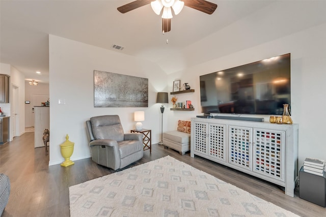 living area featuring vaulted ceiling, wood finished floors, visible vents, and baseboards