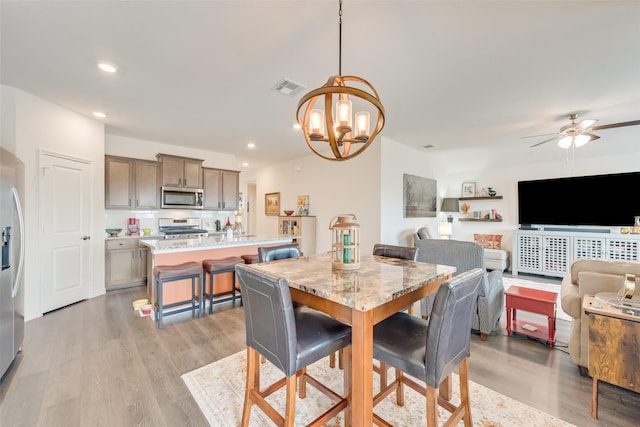 dining room with light wood-style flooring, ceiling fan with notable chandelier, visible vents, and recessed lighting