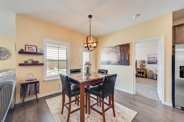 dining area featuring baseboards, dark wood-type flooring, and a notable chandelier