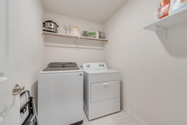 laundry area featuring laundry area, light tile patterned flooring, baseboards, and washing machine and clothes dryer