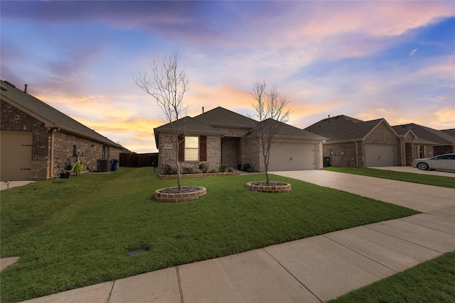 view of front of house with brick siding, central air condition unit, a lawn, a garage, and driveway