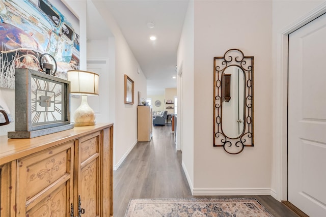 corridor with light wood-type flooring, baseboards, and recessed lighting