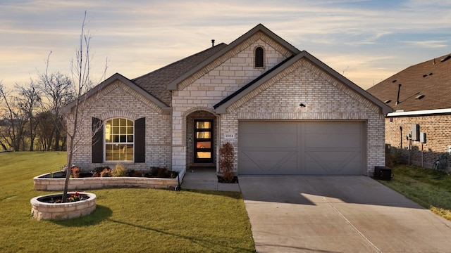 french country home featuring driveway, brick siding, a lawn, and an attached garage