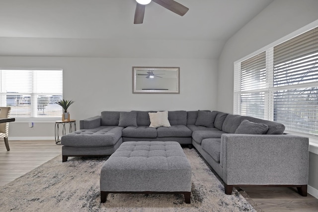 living room with light wood-type flooring, lofted ceiling, and baseboards