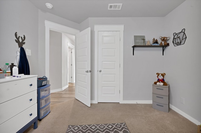 bedroom featuring visible vents, light carpet, and baseboards