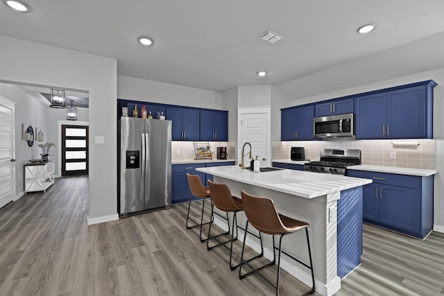 kitchen featuring blue cabinets, visible vents, a kitchen bar, and appliances with stainless steel finishes