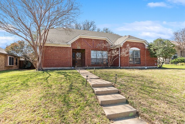 ranch-style house featuring brick siding, a front yard, and roof with shingles