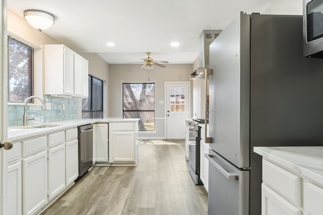 kitchen with decorative backsplash, appliances with stainless steel finishes, a peninsula, a ceiling fan, and a sink