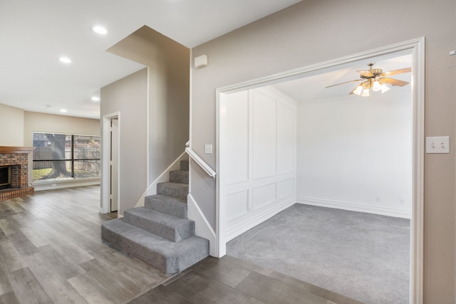 1542 Glenmore Dr, Lewisville, TX 75077 - staircase featuring ceiling fan, wood finished floors, a brick fireplace, recessed lighting, and baseboards