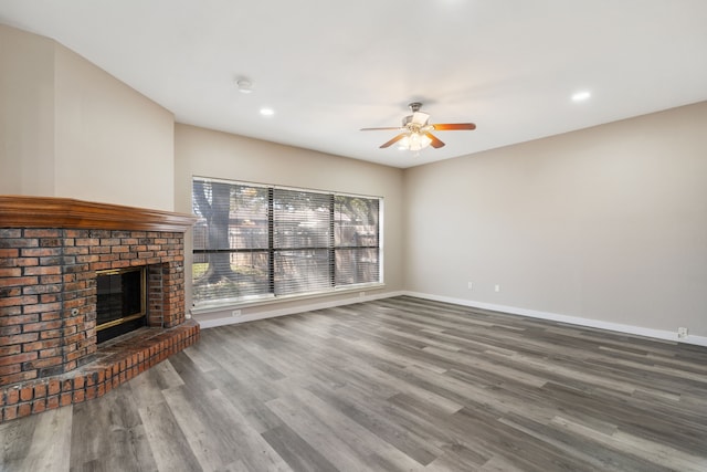 unfurnished living room featuring a brick fireplace, baseboards, ceiling fan, recessed lighting, and wood finished floors