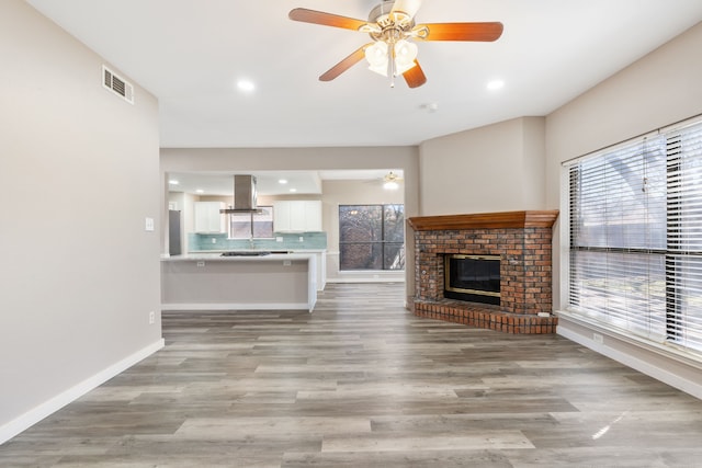 unfurnished living room with visible vents, baseboards, ceiling fan, and light wood-style flooring