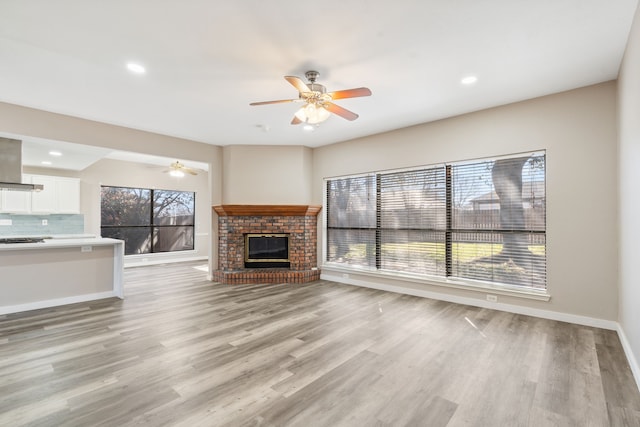 1542 Glenmore Dr, Lewisville, TX 75077 - unfurnished living room with ceiling fan, baseboards, light wood-style floors, a fireplace, and recessed lighting