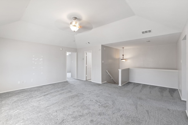 spare room with a ceiling fan, visible vents, carpet floors, baseboards, and vaulted ceiling