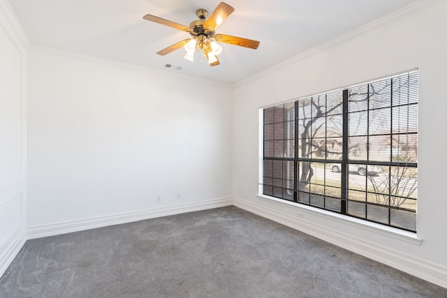 carpeted spare room featuring crown molding, a ceiling fan, visible vents, and baseboards