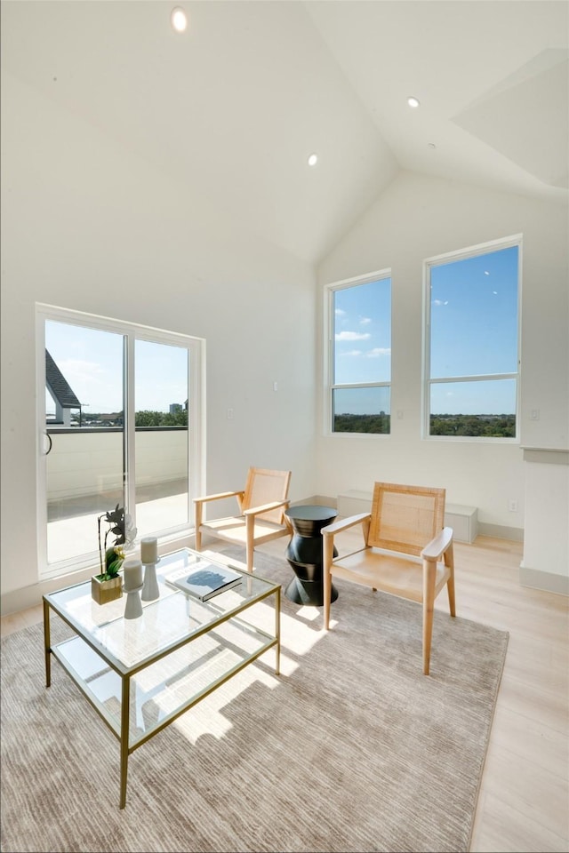 living room featuring high vaulted ceiling, recessed lighting, light wood-style flooring, and baseboards