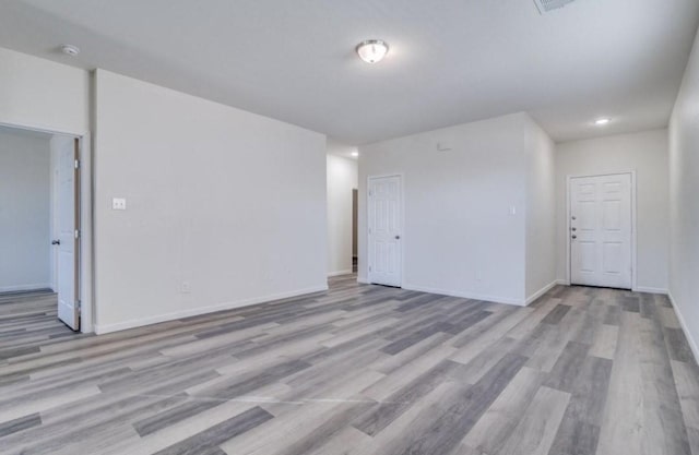 empty room featuring baseboards, wood finished floors, and recessed lighting