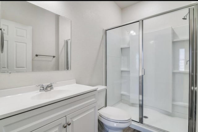 full bathroom featuring toilet, a shower stall, and vanity