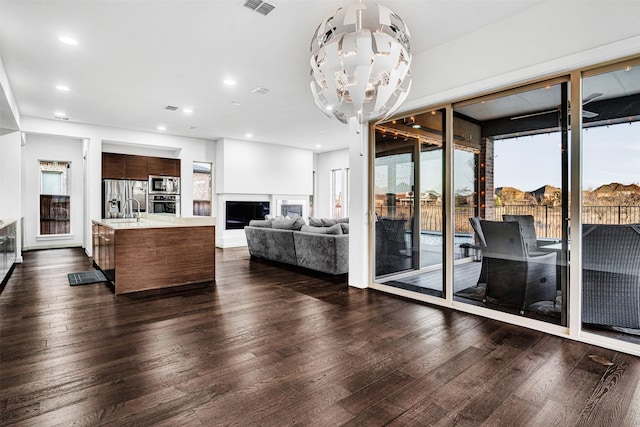 living area with visible vents, dark wood finished floors, recessed lighting, a fireplace, and a chandelier