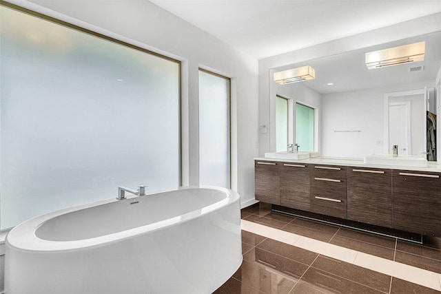 bathroom featuring double vanity, a freestanding tub, tile patterned floors, and a sink