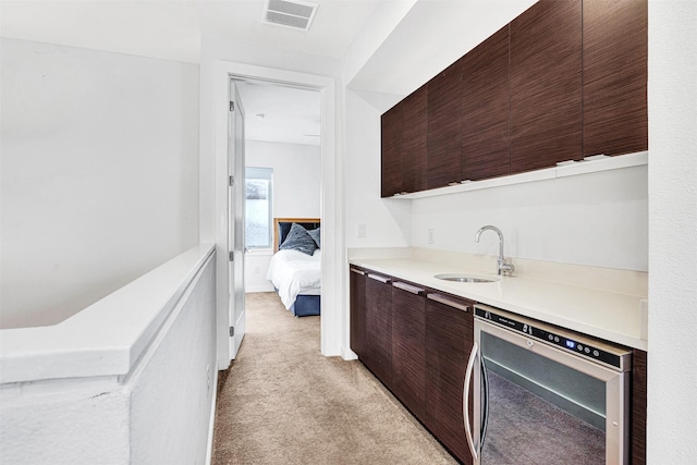 kitchen featuring visible vents, beverage cooler, light carpet, modern cabinets, and a sink