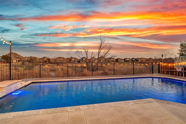 pool at dusk with fence and a fenced in pool