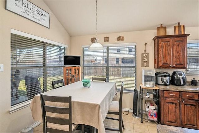 dining area with lofted ceiling, baseboards, and light tile patterned flooring