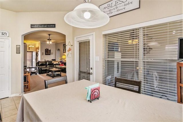 dining space with arched walkways, ceiling fan, and tile patterned flooring