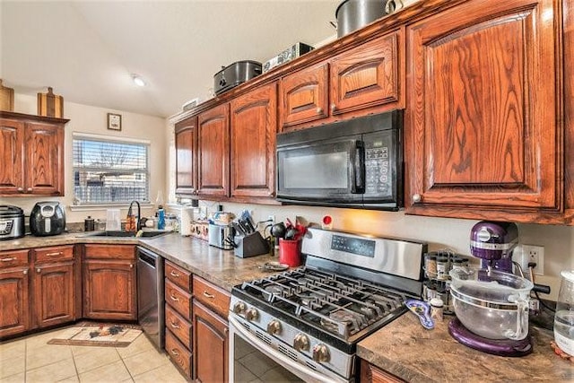 kitchen featuring appliances with stainless steel finishes, vaulted ceiling, light tile patterned flooring, and a sink