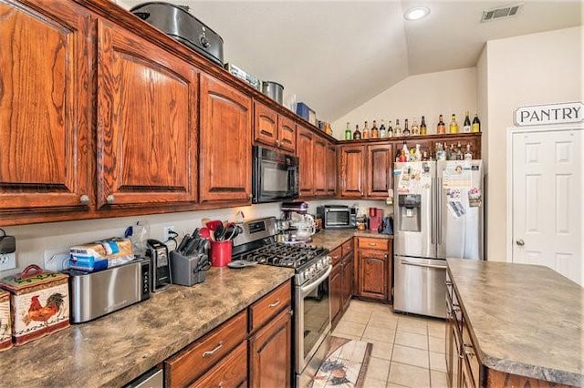 kitchen featuring stainless steel appliances, visible vents, vaulted ceiling, and light tile patterned floors