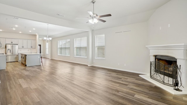 living room featuring wood finished floors, a fireplace with raised hearth, visible vents, and baseboards