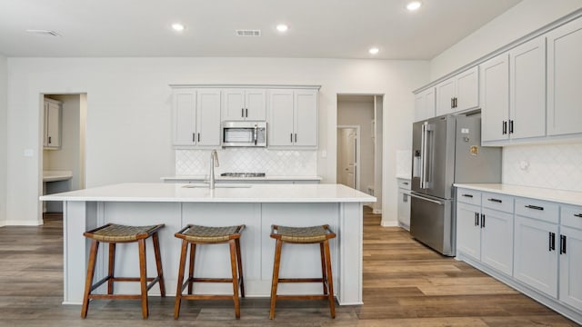 kitchen featuring visible vents, dark wood finished floors, a breakfast bar, light countertops, and appliances with stainless steel finishes