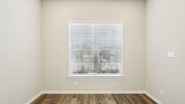 empty room with dark wood-style floors and baseboards