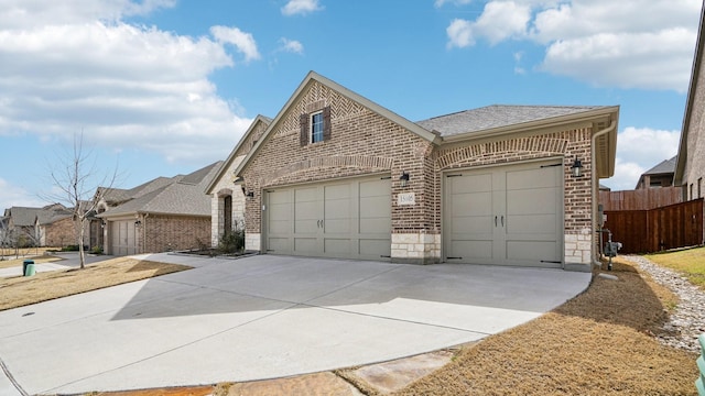 view of front of property featuring fence, concrete driveway, a shingled roof, a garage, and brick siding