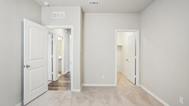 unfurnished bedroom featuring visible vents, a walk in closet, baseboards, and carpet floors