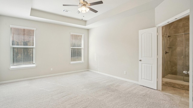 unfurnished bedroom featuring visible vents, baseboards, carpet floors, multiple windows, and a raised ceiling