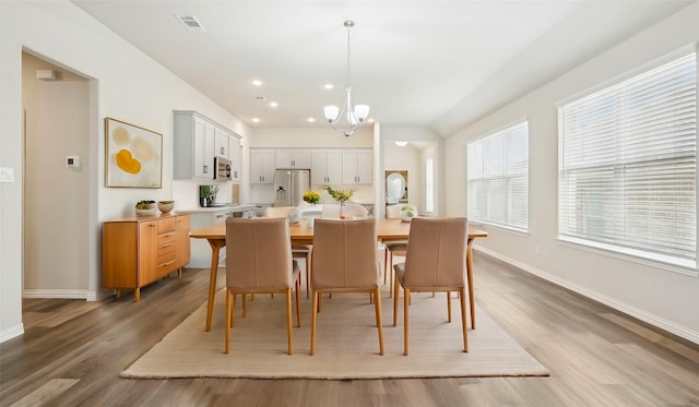 dining space with visible vents, an inviting chandelier, baseboards, and wood finished floors