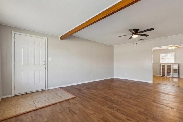 empty room featuring beamed ceiling, wood finished floors, visible vents, and baseboards