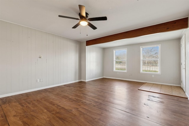 unfurnished room with beam ceiling, ceiling fan, baseboards, and wood finished floors